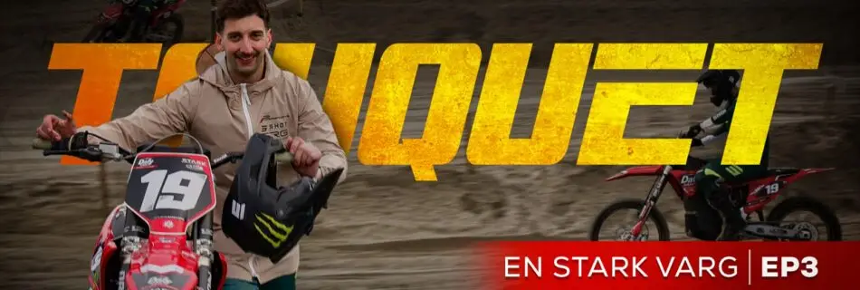 Pilote de motocross avec sa moto rouge.