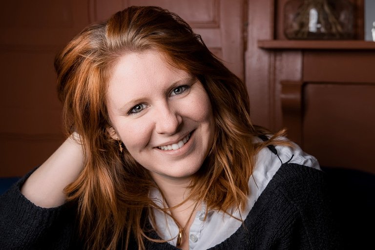 Femme rousse souriante la main dans ses cheveux